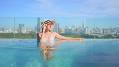 asian woman relax in infinity-edge pool with bangkok cityscape in background