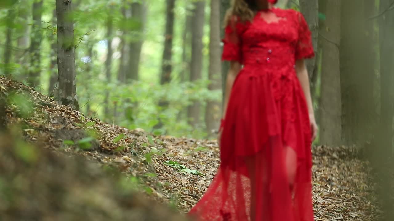 Woman Walking In Mysterious Forest. Woman in red long dress walking in mysterious forest