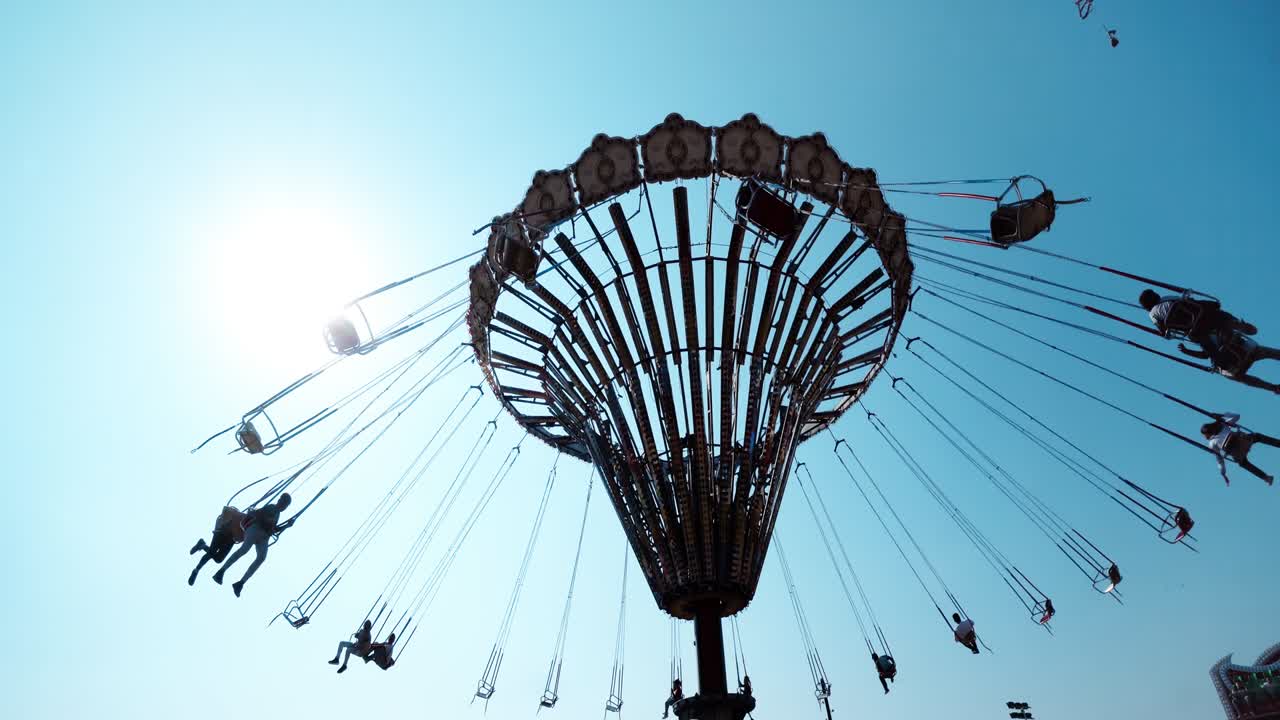 силуэты весело ездят на цепной карусели в парке развлечений