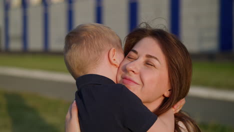 little boy hugs smiling mother on street slow motion