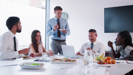 Hombres-Y-Mujeres-De-Negocios-Reunidos-En-Una-Moderna-Sala-De-Juntas-Durante-Un-Almuerzo-De-Trabajo-Filmado-En-Cámara-Lenta.