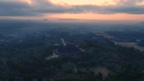 orbit drone shot of borobudur temple with magical light of sunrise sky in misty morning