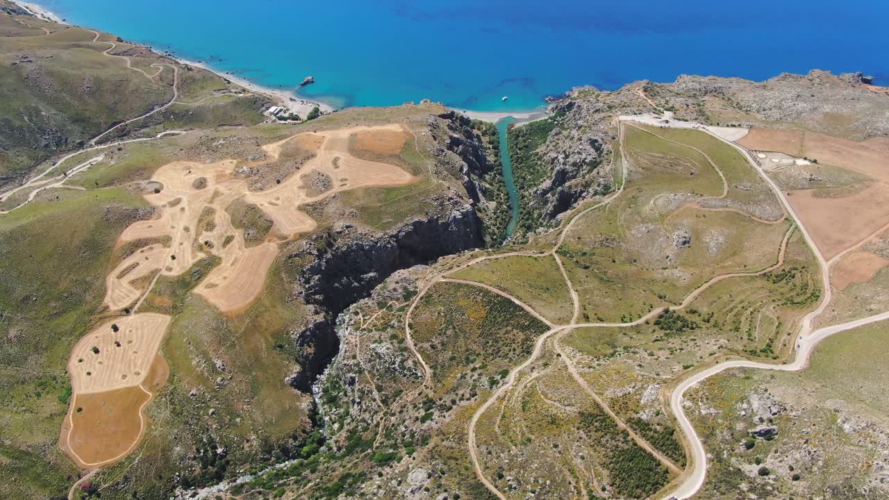 River Flows Into The Ocean Near Winding Roads. Aerial Drone Shot Of Crete, Greece
