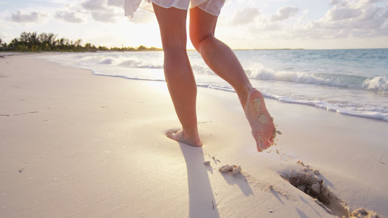 Gambe di donna caucasica che cammina a piedi nudi sulla spiaggia