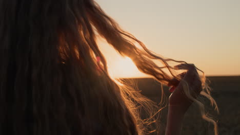 young woman looks at her hair in the sun, holds a lock of hair in her hand