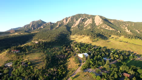 drone invirtiendo sobre un vecindario en boulder, colorado, ee.uu. en una mañana de verano con las montañas de hierro planas y el parque chautauqua en el fondo