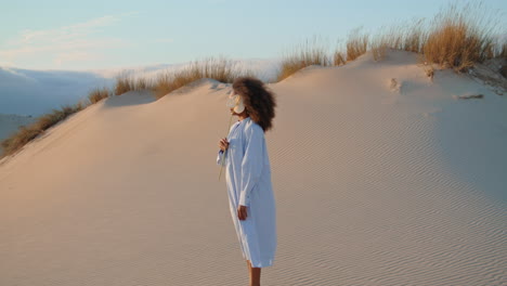 Woman-holding-flower-at-summer-sand-desert.-Calm-girl-hiding-face-behind-calla