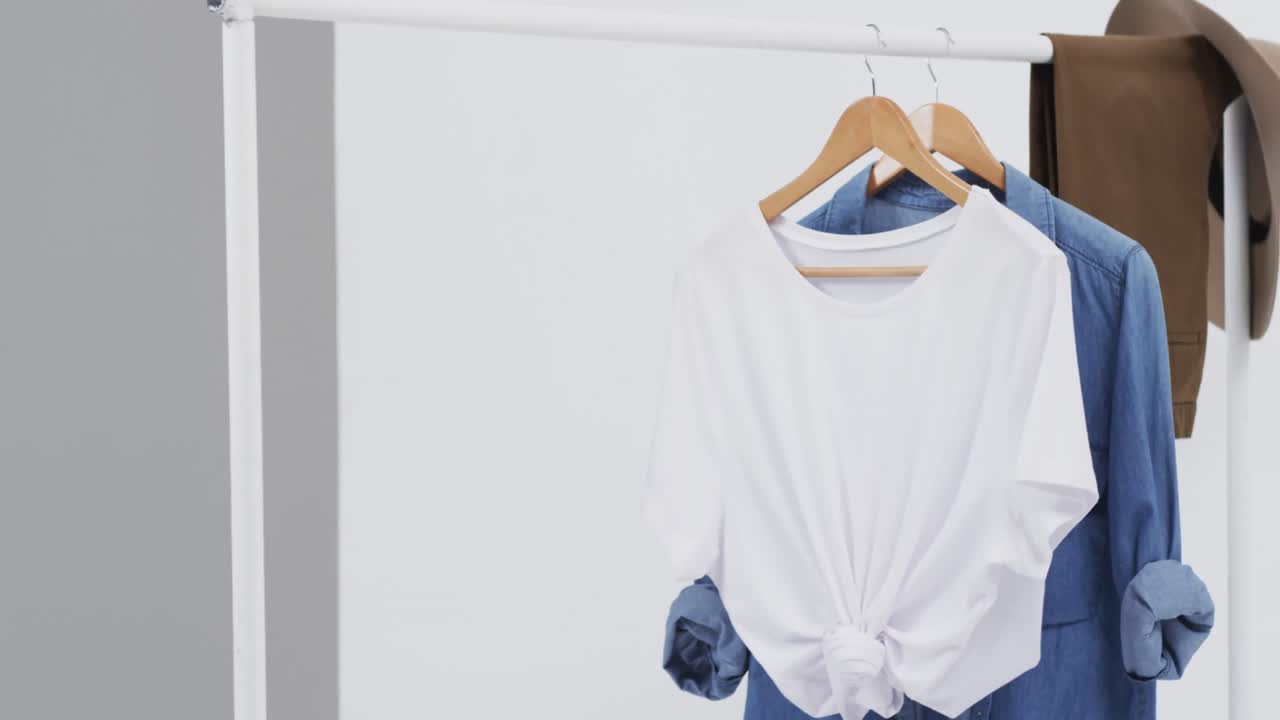 video de camiseta blanca y denim en perchas, sombrero y espacio de copia sobre fondo blanco