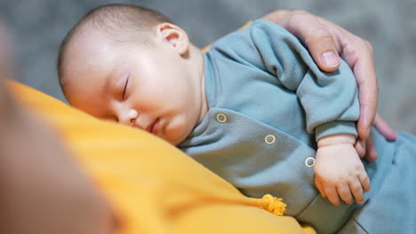 adorable little toddler sleeping in father's arms. small child resting peacefully in dad's hands at grey blurred backdrop.
