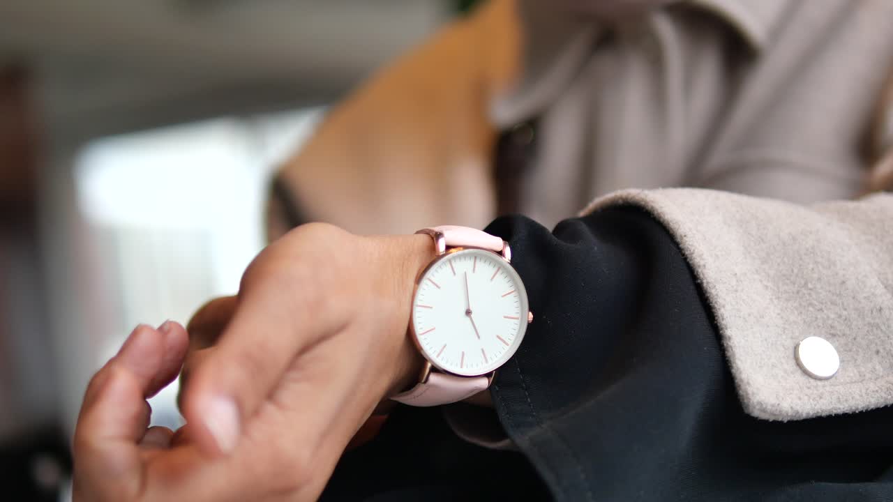 A close-up of a person wearing a pink wrist watch