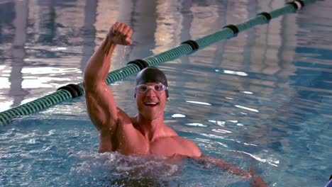 fit happy swimmer jumping up and cheering in the pool