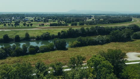 calm river bends through flat countryside near zagreb with trees and grassy fields in summer light