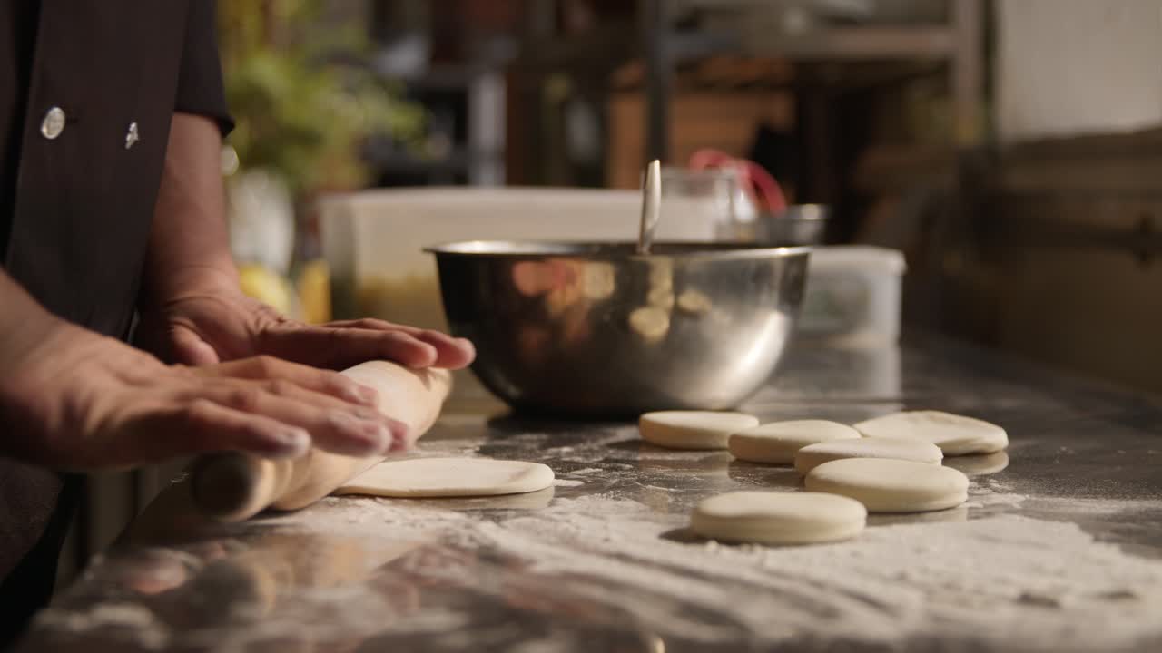 Man's hands roll out the dough for dumplings