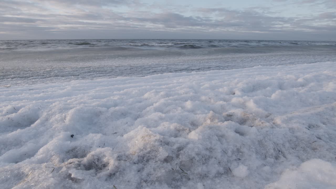 해변에 굴러다니는 얼음 덮인 바다 파도