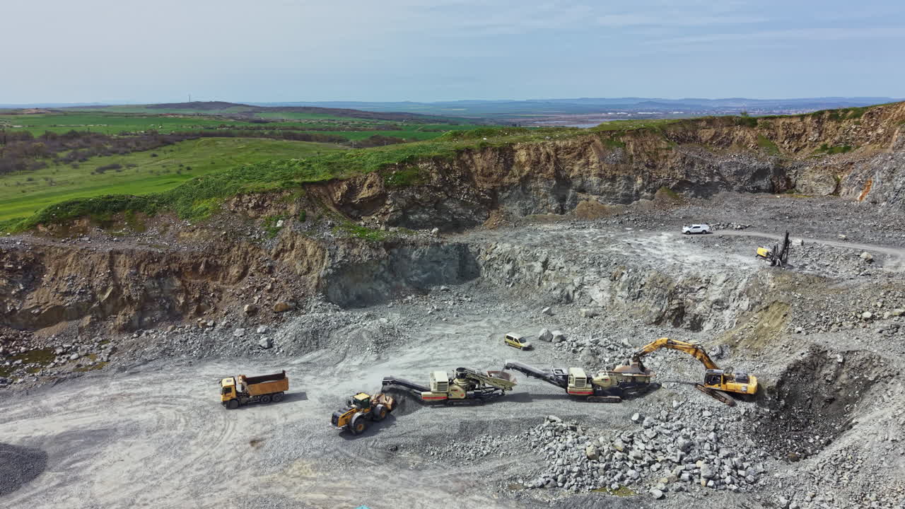Granite quarry site with heavy machinery working and natural landscape in the background