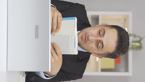 video vertical de un trabajador de oficina en casa leyendo un libro.