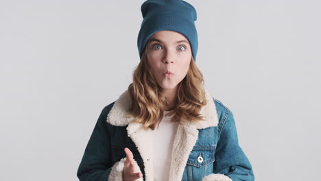 surprised teenage caucasian girl wearing denim jacket and beanie.