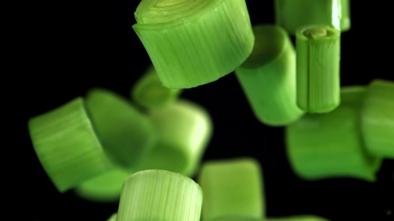 Fresh Chopped Green Onions Falling Against Black Background