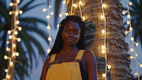 stylish african american woman posing under string lights