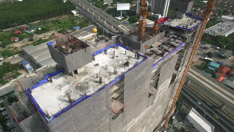 aerial view of modern high rise building under construction in the busy city centre business district with workers, scaffolding and crane