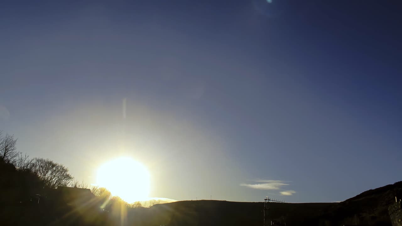 timelapsed Sunset with a silhouetted hillside framing the bottom of shot.