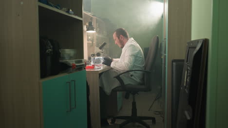 a middle view of a technician in a lab coat meticulously working on electronic components under a microscope in a well-equipped lab, the room is filled with tools in the shelf