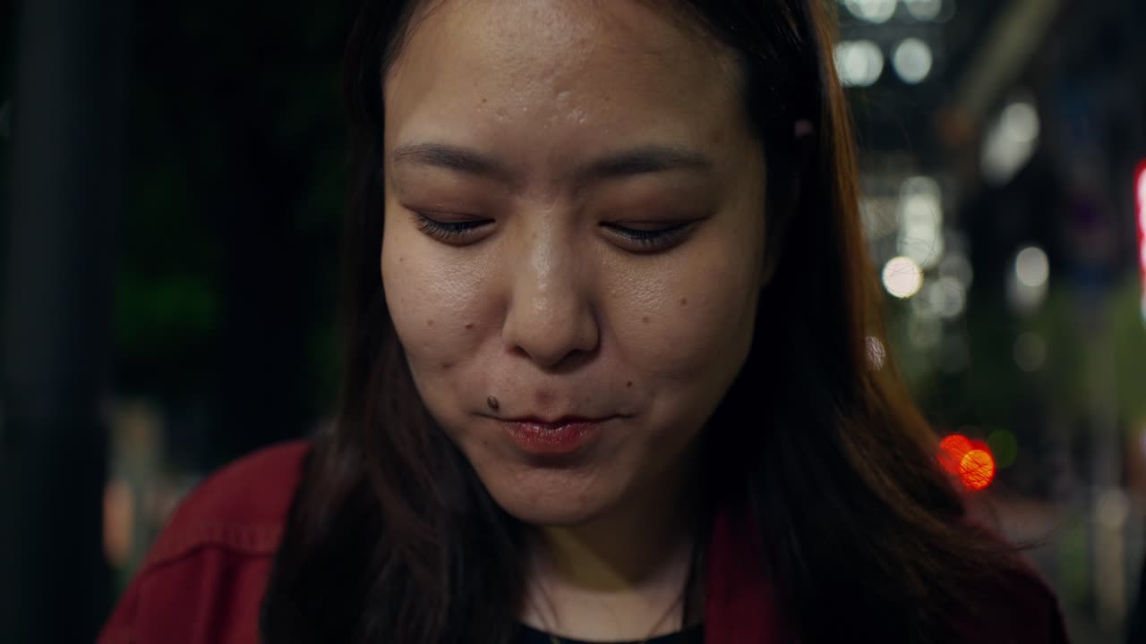 Woman Eating Noodles Outside at Night