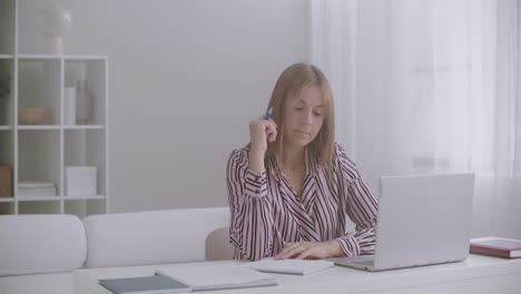 Una-Estudiante-Está-Aprendiendo-En-Línea-Viendo-Una-Lección-En-Video-En-Una-Computadora-Portátil-Y-Escribiendo-En-Un-Cuaderno-De-Ejercicios-Educación-Electrónica-Para-Jóvenes