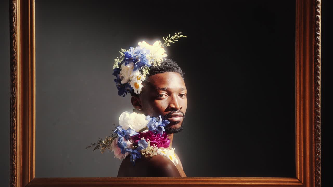 Ritratto di uomo afroamericano adornato con fiori all'interno di una cornice.