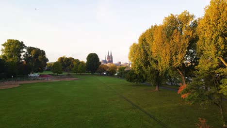 vuelo de avión no tripulado a través de un hermoso parque en colonia, alemania durante la puesta de sol hacia el famoso kölner dom