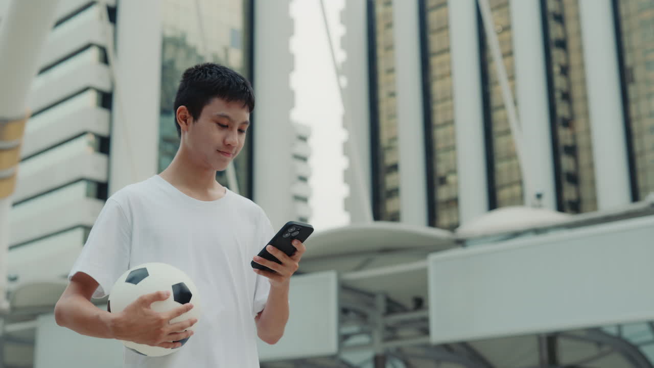Boy with ball and phone in city