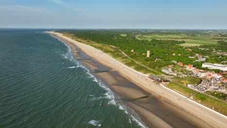 aerial shot of changing tides outside a picturesque little coastal town in a green, rural area, on a beautiful summer day