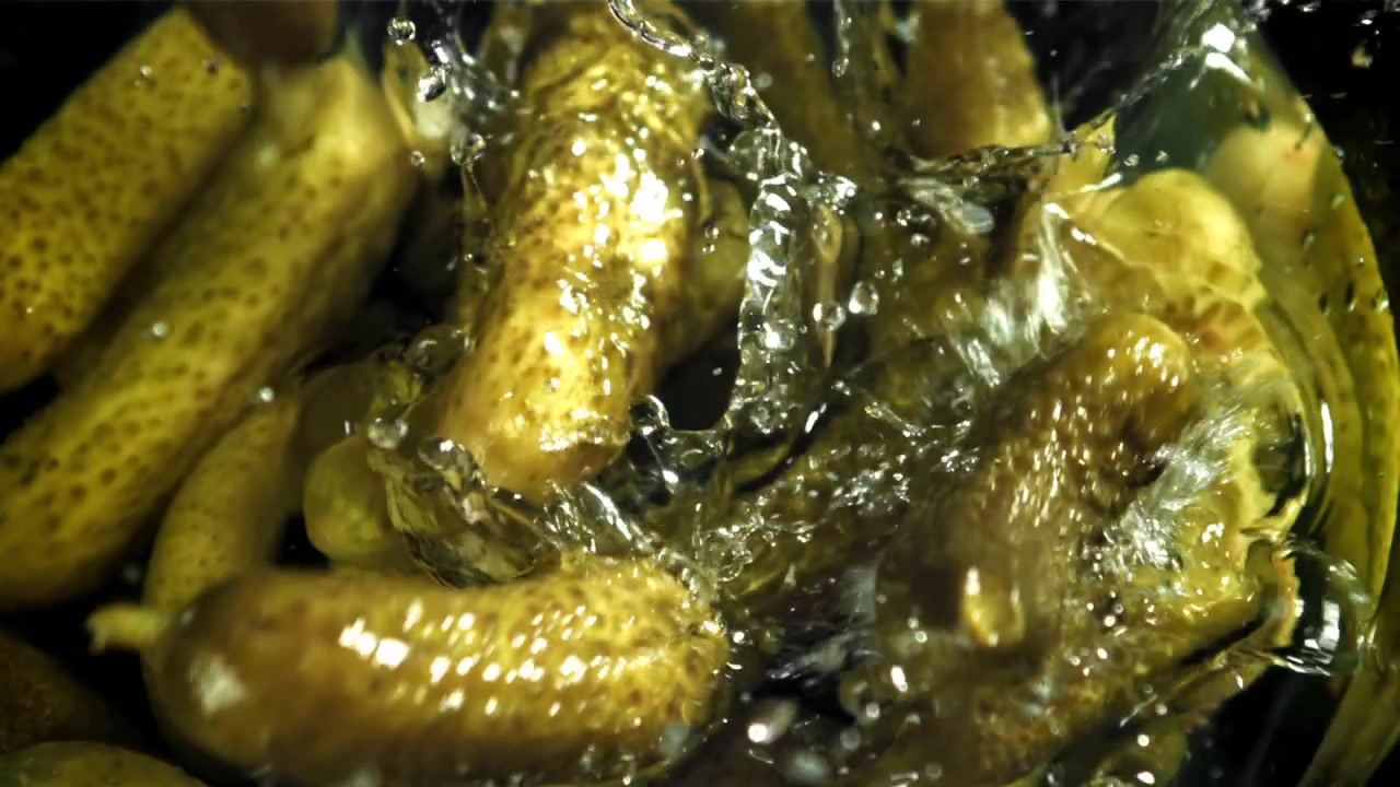 Cornichons frais tombant et éclaboussant dans la saumure au ralenti