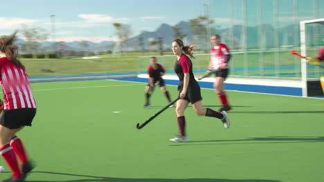 female hockey players competing intensely on outdoor field, showcasing teamwork