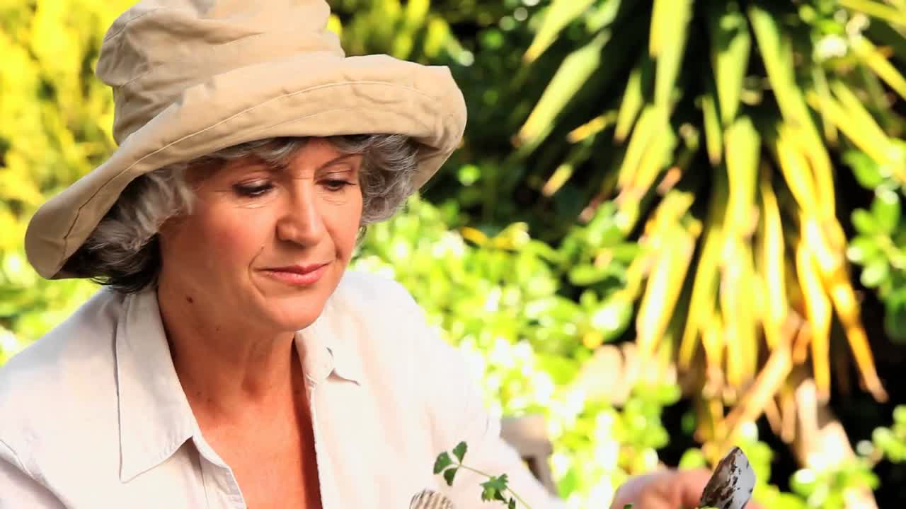 행복 한 성숙 한 여자 는 식물 을  ⁇ 비 하고 있다