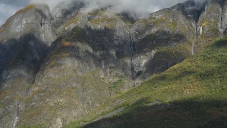 Close-up-view-of-a-steep-mountain-slope-with-a-autumn-forest-and-waterfalls