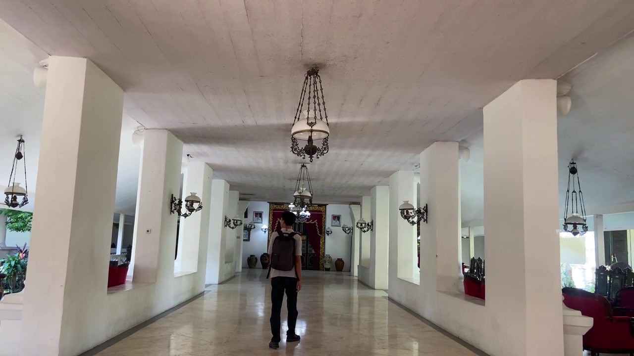 Jovem com Mochila Caminha por Corredor de Grande Hotel