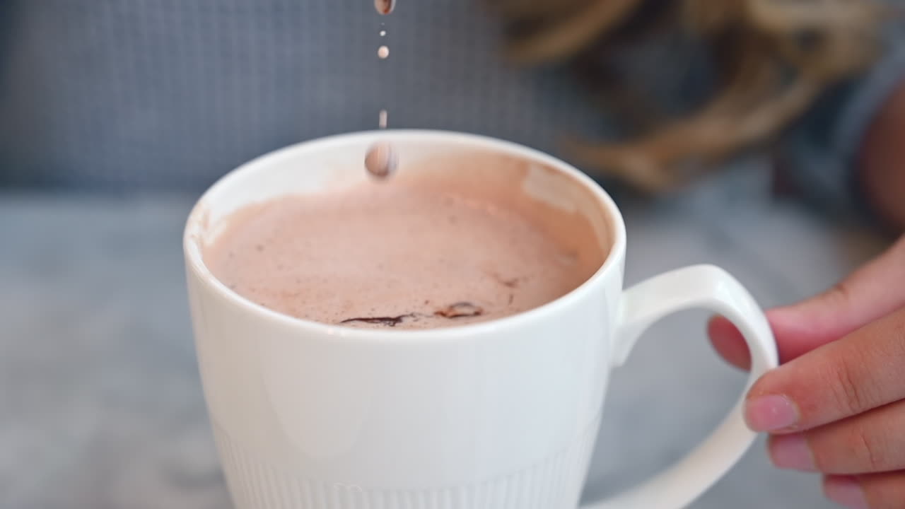 Donna che mescola cioccolato nel latte in una tazza bianca in un bar