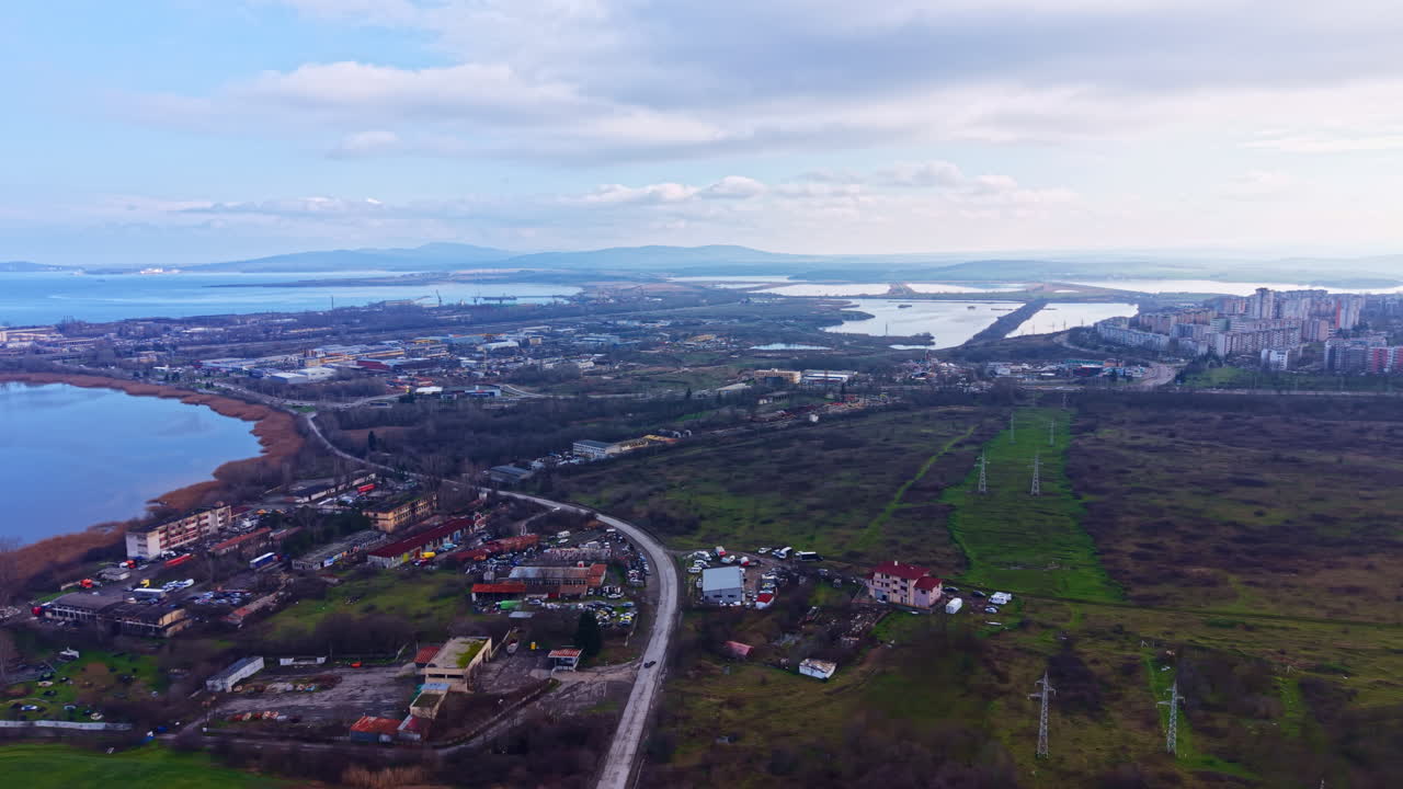 Bird's eye view of a landscape with water, buildings, and roads in a rural area near a city during daytime