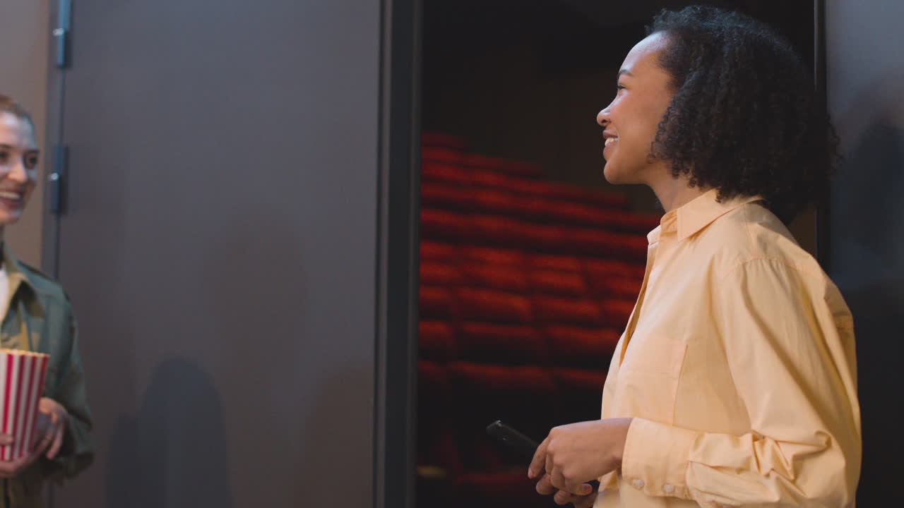 pareja feliz con caja de palomitas de maíz que muestra el boleto de cine qr en un teléfono celular para el ujier de cine femenino