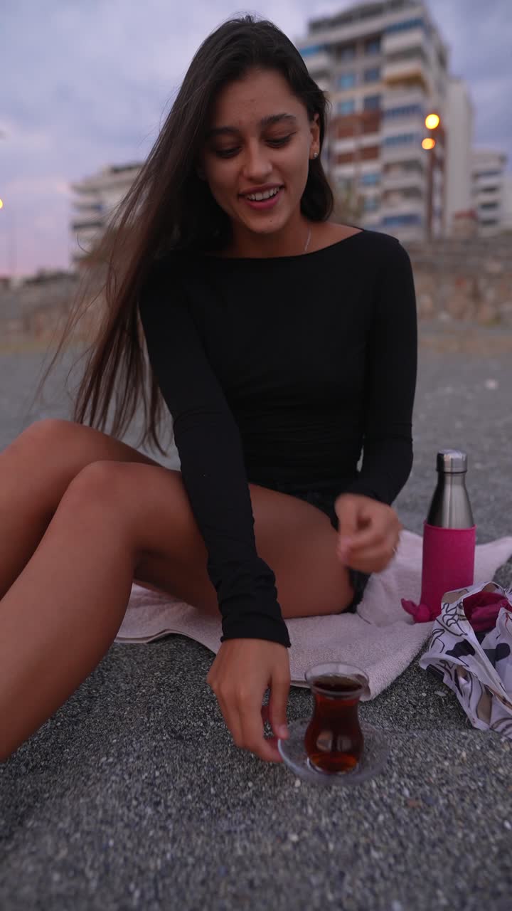 mujer disfrutando de té turco en la playa al atardecer