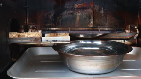 close up of wood puck smoker with a stainless basin of hot water