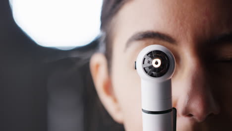 woman using otoscope for examination, close up, half of face