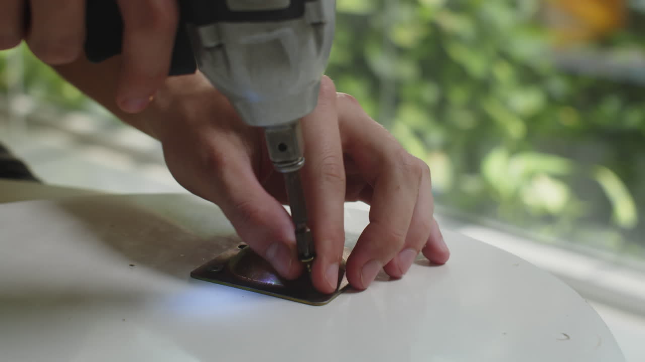 Hands of Person Using Screw Gun when Assembling Table