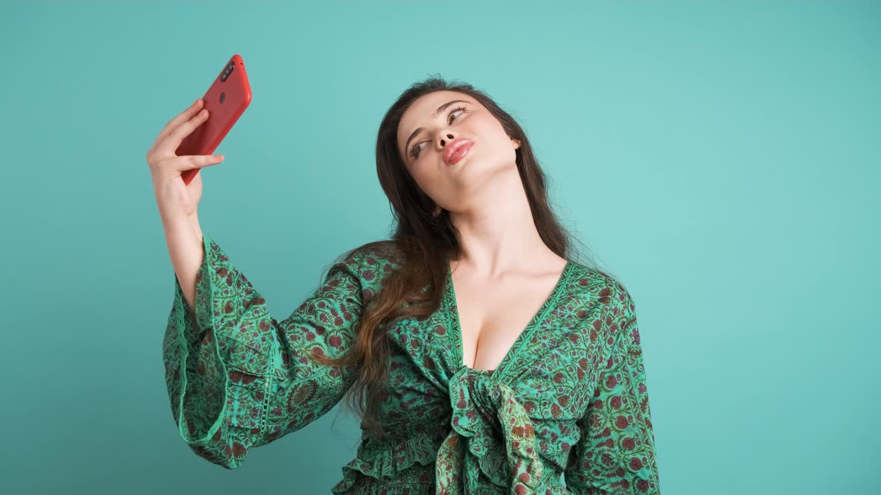 Happy woman taking selfie with smartphone in blue studio