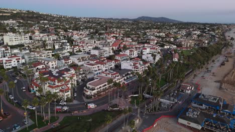 a drone-captured aerial view of the pier bowl neighborhood in san clemente, california, at twilight, showcasing spanish-style architecture, beach access, and the vibrant coastal community.