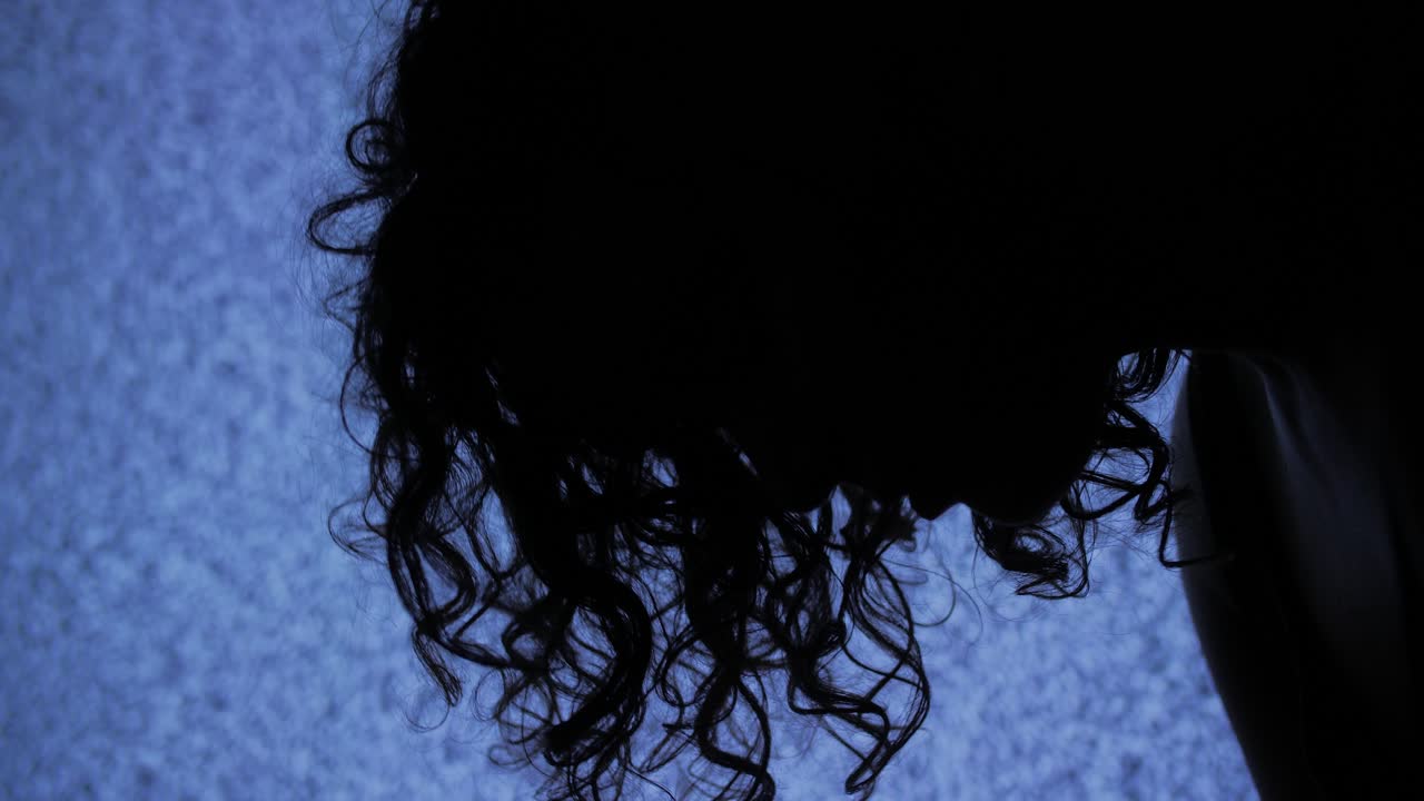 Person's Silhouette with Curly Hair Against Blue Static Screen