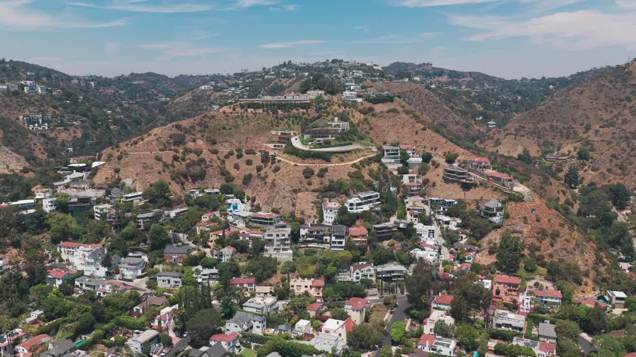 Wide descending and panning aerial shot of upscale hillside homes in Hollywood Hills, California. 4K