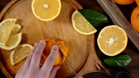 hands men cut ripe orange on a cutting board.