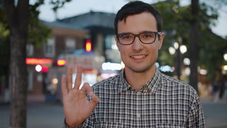 man smiling and showing ok gesture in the city at night